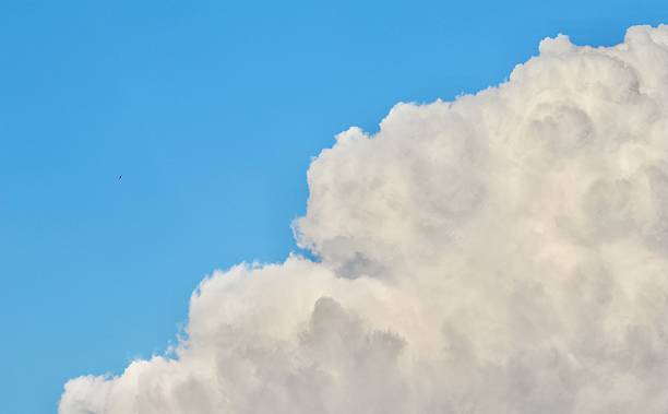 istock A bright, fluffy, white cumulonimbus cloud dominates the lower right corner, creating a strong diagonal division with the vibrant blue sky 2247597841