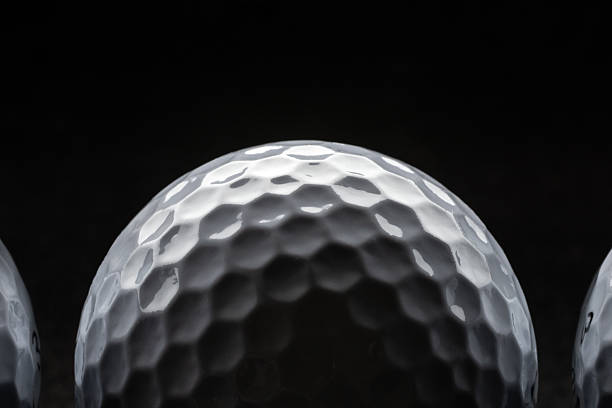 A golf ball on a tee isolated on black background.