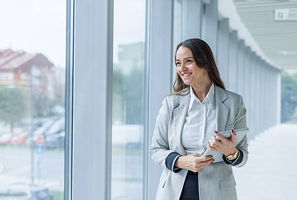 istock Businesswoman standing in modern office corridor holding tablet 2247601462