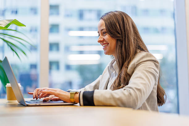 istock Woman smiling while typing on laptop in modern office 2247601476