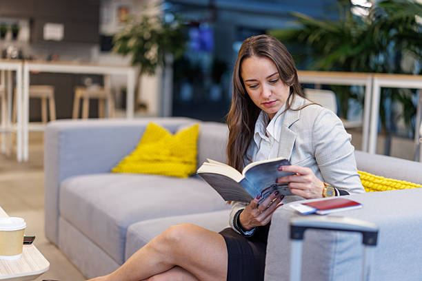 istock Woman reading book while waiting at airport lounge 2247601494