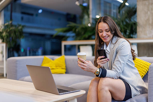 istock Businesswoman taking coffee break checking smartphone in office lobby 2247601589
