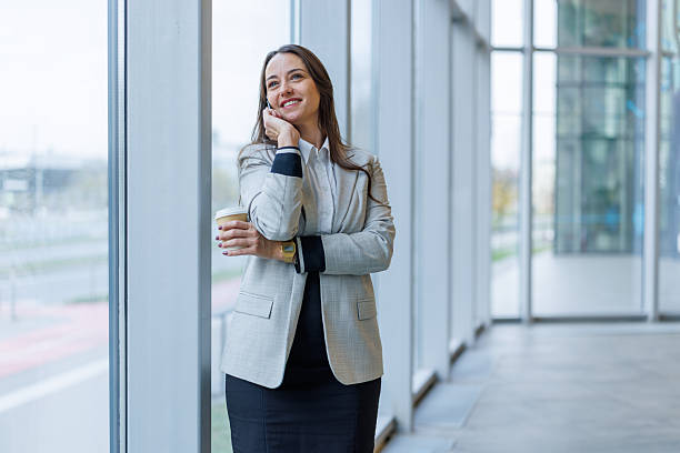 istock Businesswoman talking on phone holding coffee cup in office 2247605535