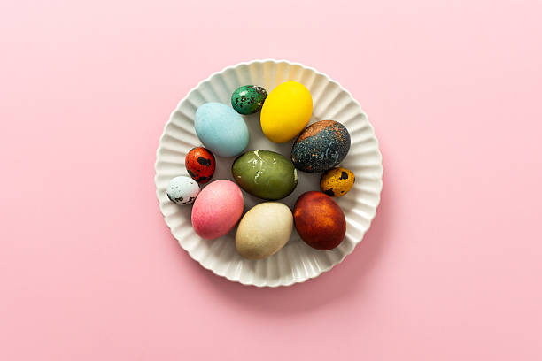 istock A collection of vibrant Easter eggs in various colors is artfully arranged on a white plate, set against a soft pink background, capturing the essence of the holiday's decorations 2247607627