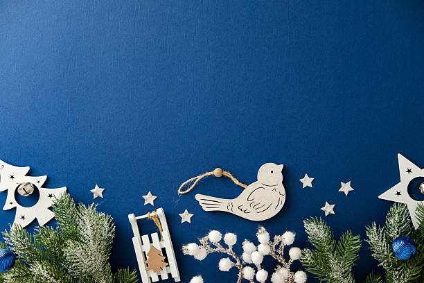 Bottom border of wooden Christmas ornaments on solid blue background