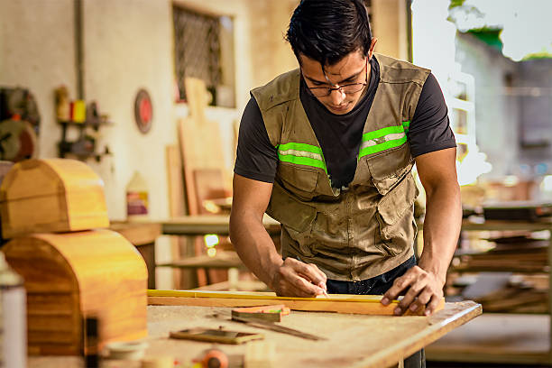 istock Carpenter with glasses taking measurements at the workbench. Young cabinetmaker measuring a piece with a tape measure in the workshop 2247608513