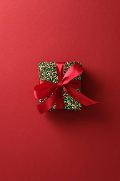 istock Shiny Christmas gift box with red ribbon on a clean red background. 2247608984