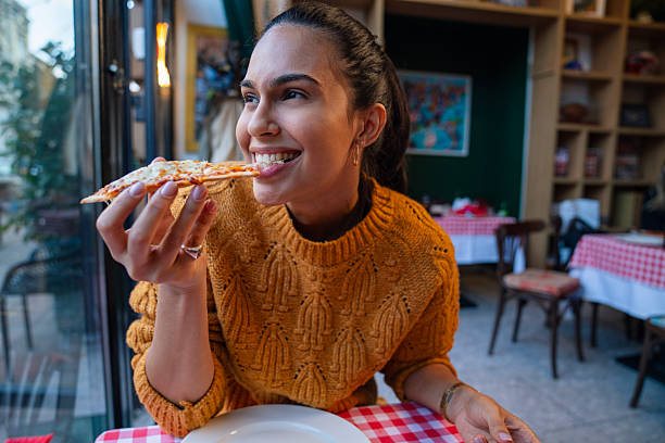 istock Happy young woman eating pizza 2247609876