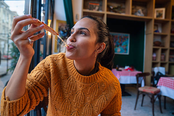 istock Happy young woman eating pizza 2247609890