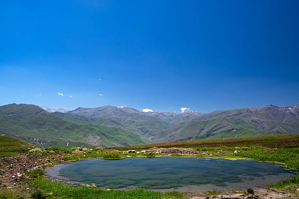 Quiet pond and green hills near Qriz, Azerbaijan, captured in bright daylight.