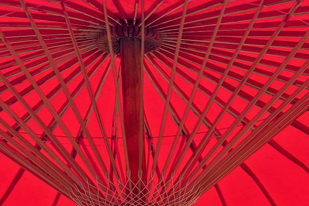 Coral colored umbrella before blue background. Horizontal composition.