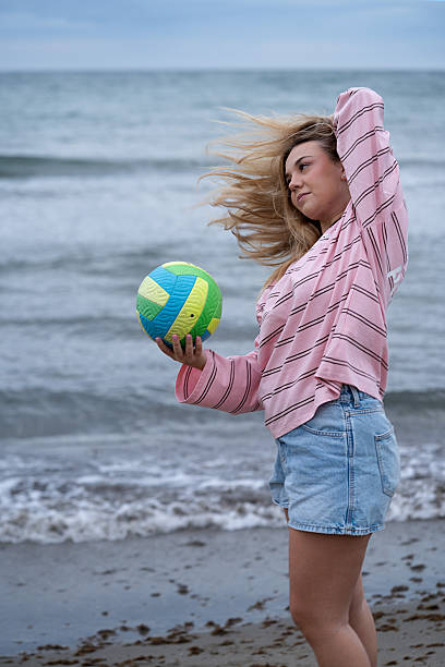 istock Woman playing volleyball on beach with wind blowing hair 2247617607