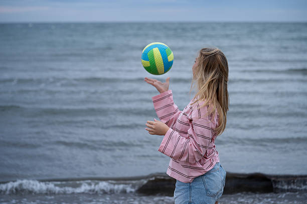 istock Girl playing with ball at ocean shore 2247617611