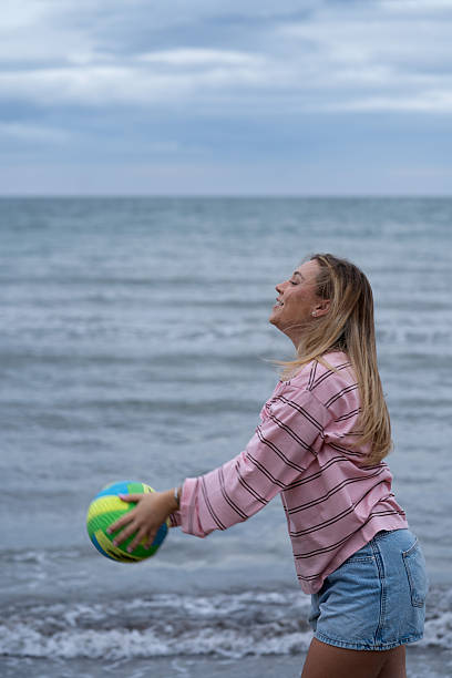 istock Young woman playing with ball on beach 2247617633