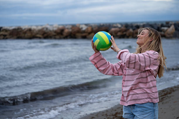 istock Woman playing volleyball on beach with breakwater 2247617638