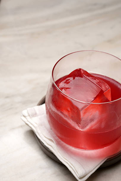 istock Vibrant red cocktail with a large, clear ice cube, served on a coaster and napkin 2247618037