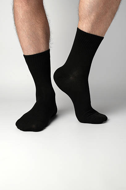 istock Man's legs in black athletic socks on a white background 2247619587
