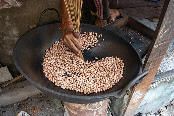 istock worker roasting and selling fresh roasted peanuts at a road side stall in Kolkata, West Bengal, India 2247622454
