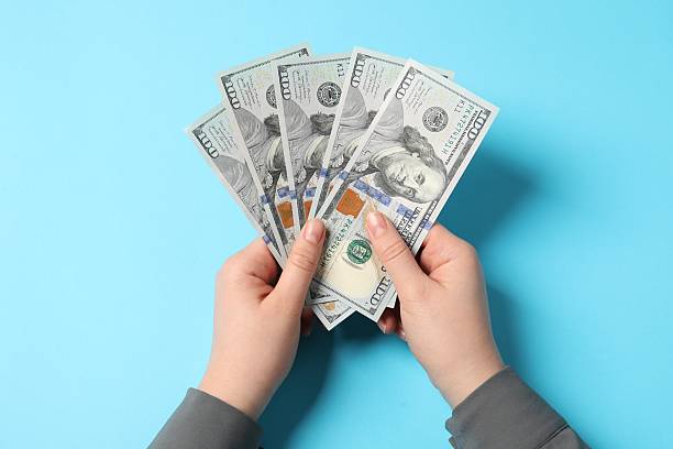 istock Money exchange. Woman holding dollar banknotes on light blue background, top view 2247623355
