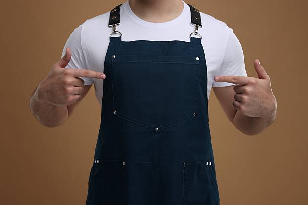 istock Man pointing at kitchen apron on brown background, closeup. Mockup for design 2247625026