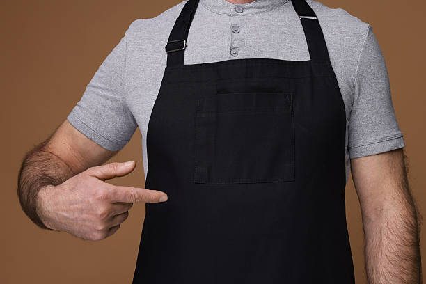 istock Man pointing at kitchen apron on brown background, closeup. Mockup for design 2247625034