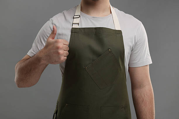 istock Man in kitchen apron showing thumb up on grey background, closeup. Mockup for design 2247625059