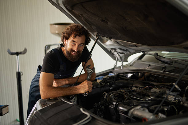 istock Car mechanic smiling and holding a wrench while repairing a car engine 2247625326