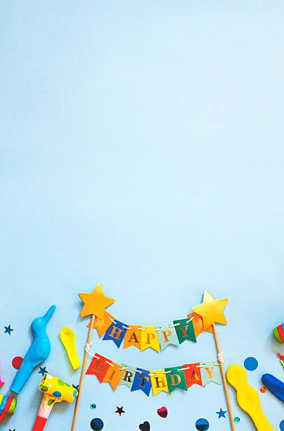 Festive birthday decorations with a Happy Birthday banner, balloons, confetti, and party blowers arranged on a light blue background perfect for invitations, greeting cards, party promotions, and celebration-themed designs.