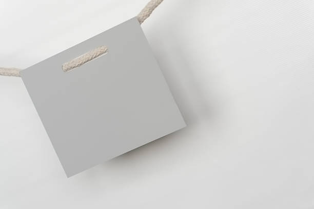 istock Empty gray paper card hangs from a rope against a white background. 2247628350