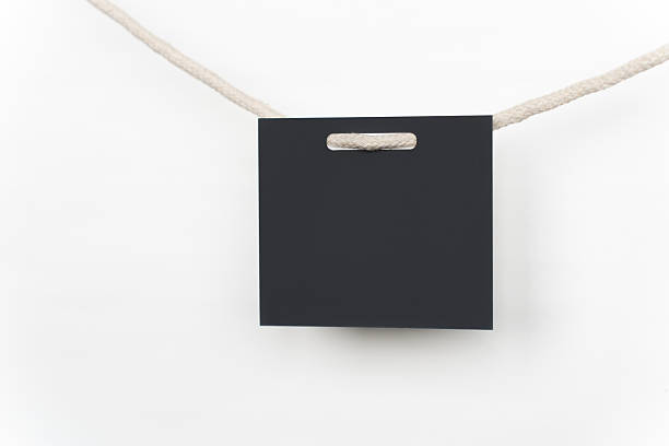 Empty black paper card hangs from a rope against a white background.