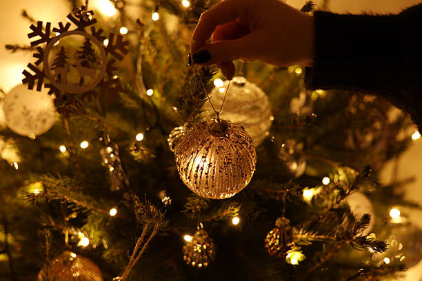 istock Hand attaching a golden ornament decoration to a Christmas tree 2247629316