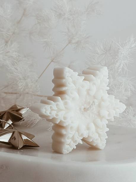 istock Close-up elegant white snowflake-shaped candle Christmas decoration arranged on a table with metal stars 2247629755