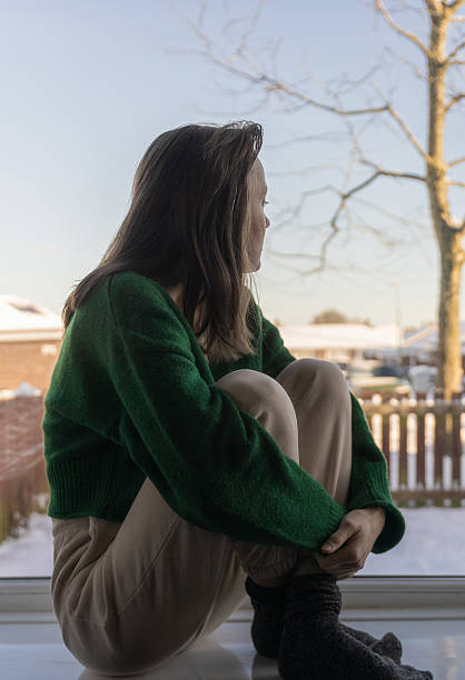istock Thoughtful sad woman sitting on a windowsill 2247632133