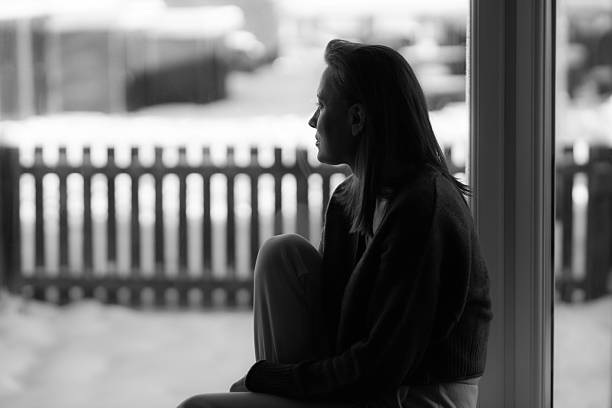 istock Thoughtful sad woman sitting on a windowsill 2247632216