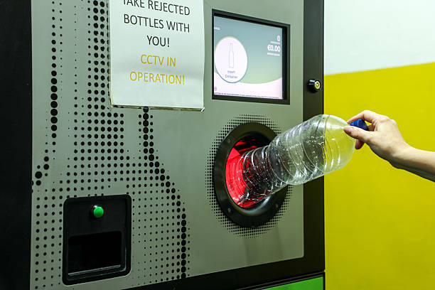 istock Efficient recycling: a person inserts a plastic bottle into a modern reverse vending machine with a glowing red intake. Clear signs and clean design highlight sustainability and eco-friendly habits. 2247632542