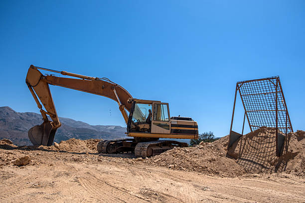 A large excavator is parked in the area of a road construction project and a large water pipe system, large machinery, road construction, water pipe system, excavator, earthmoving vehicle