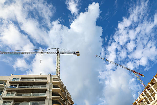 istock Two massive construction cranes silhouetted against the open sky, lifting materials to new heights and reflecting progress, innovation, and ambitious large-scale building projects. 2247632585