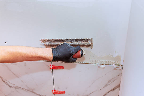 istock Skilled worker applying adhesive to wall for tile installation in modern bathroom renovation 2247633296