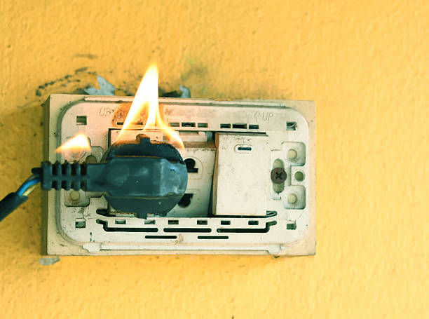 istock A wall outlet is on fire, with flames and small smoke. 2247633640
