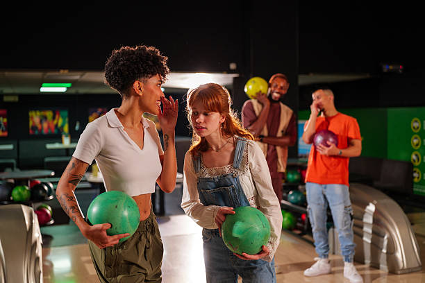 istock Group of young friends laughing and sharing secrets while enjoying a fun night out at the bowling alley, filled with excitement and joy 2247633966