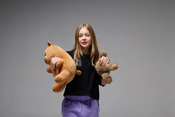 istock Caucasian young girl holding stuffed animals on grey background 2247635675