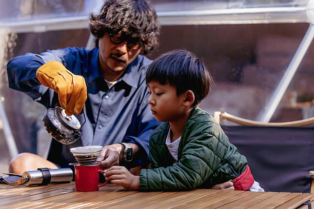 Parents and children brewing coffee at a campsite