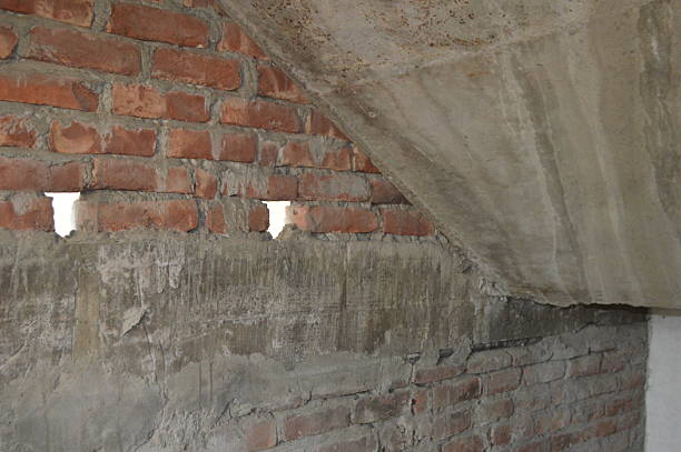 A raw brick interior with concrete beams and small daylight openings, capturing an industrial, unfinished construction scene and rugged textures of brick and concrete.