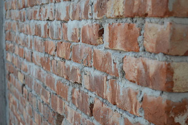 istock A close-up of a rustic red brick wall with weathered mortar, showing rough texture and warm tones. 2247639632