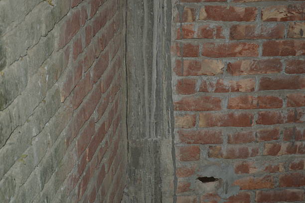 A close-up of a rustic red brick wall with weathered mortar, showing rough texture and warm tones. Ideal background for urban architecture, construction, or design projects conveying durability and vintage charm.