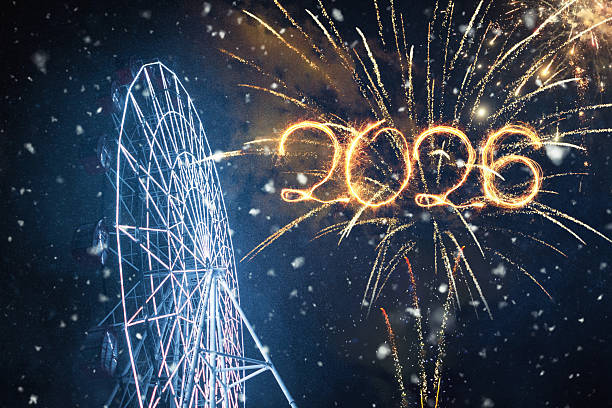 Happy New Year 2026 Celebration. Fireworks display with numbers 2026 written in light against a night sky with snow and a brightly lit Ferris wheel. Festive winter holiday scene