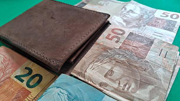 istock Folded Brazilian Real banknotes and a leather wallet 2247643429