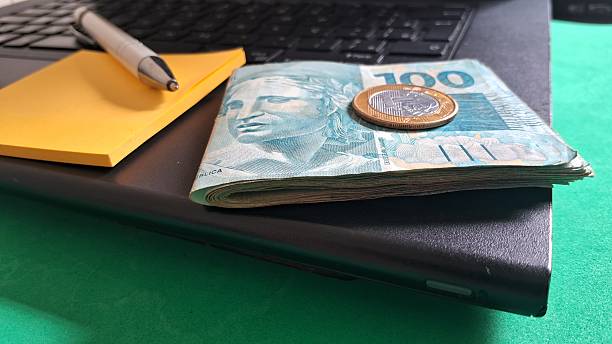 istock Brazilian Real Currency on Laptop Keyboard with Pen and Sticky Note 2247643583