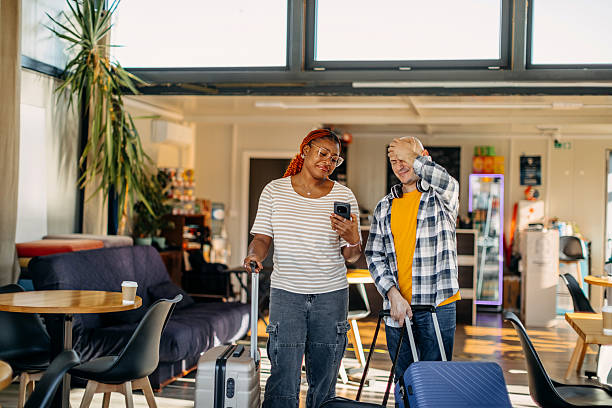 istock Multiracial couple waiting for transportation at cafe going on vacation with suitcases and looking up on the screen when is their flight leaving 2247643593