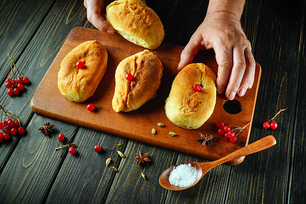istock Hands carefully arrange freshly baked bread rolls topped with cherries, surrounded by spices and salt on a wooden cutting board, showcasing a delightful culinary moment 2247643891